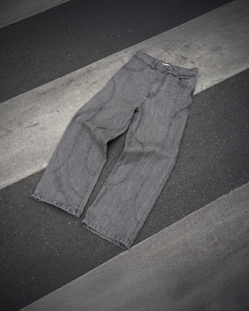 Jeans gris avec des détails de couture sur un sol en béton. 